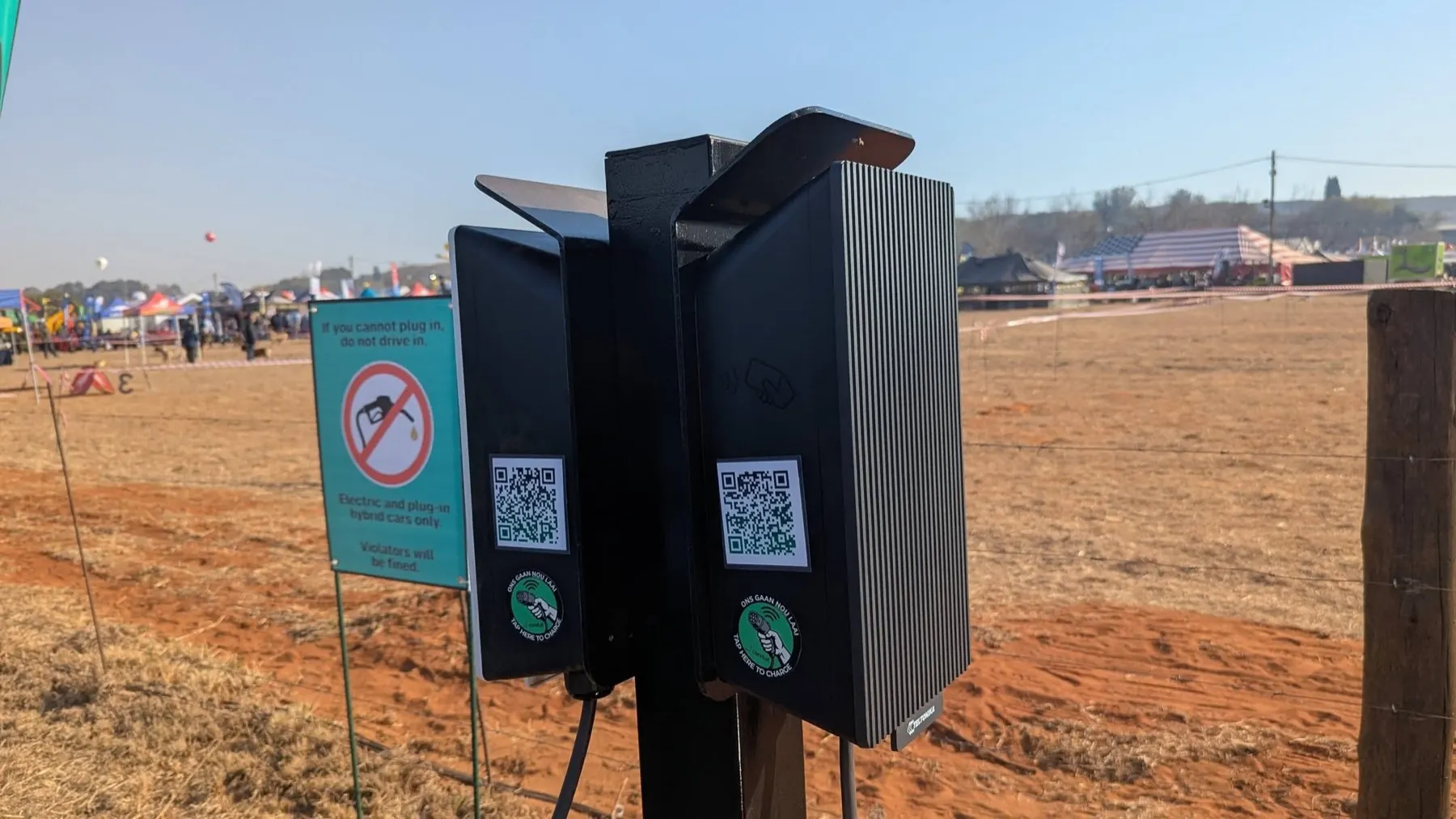 Two Conduit charge posts with QR code stickers reading “tap here to charge”
