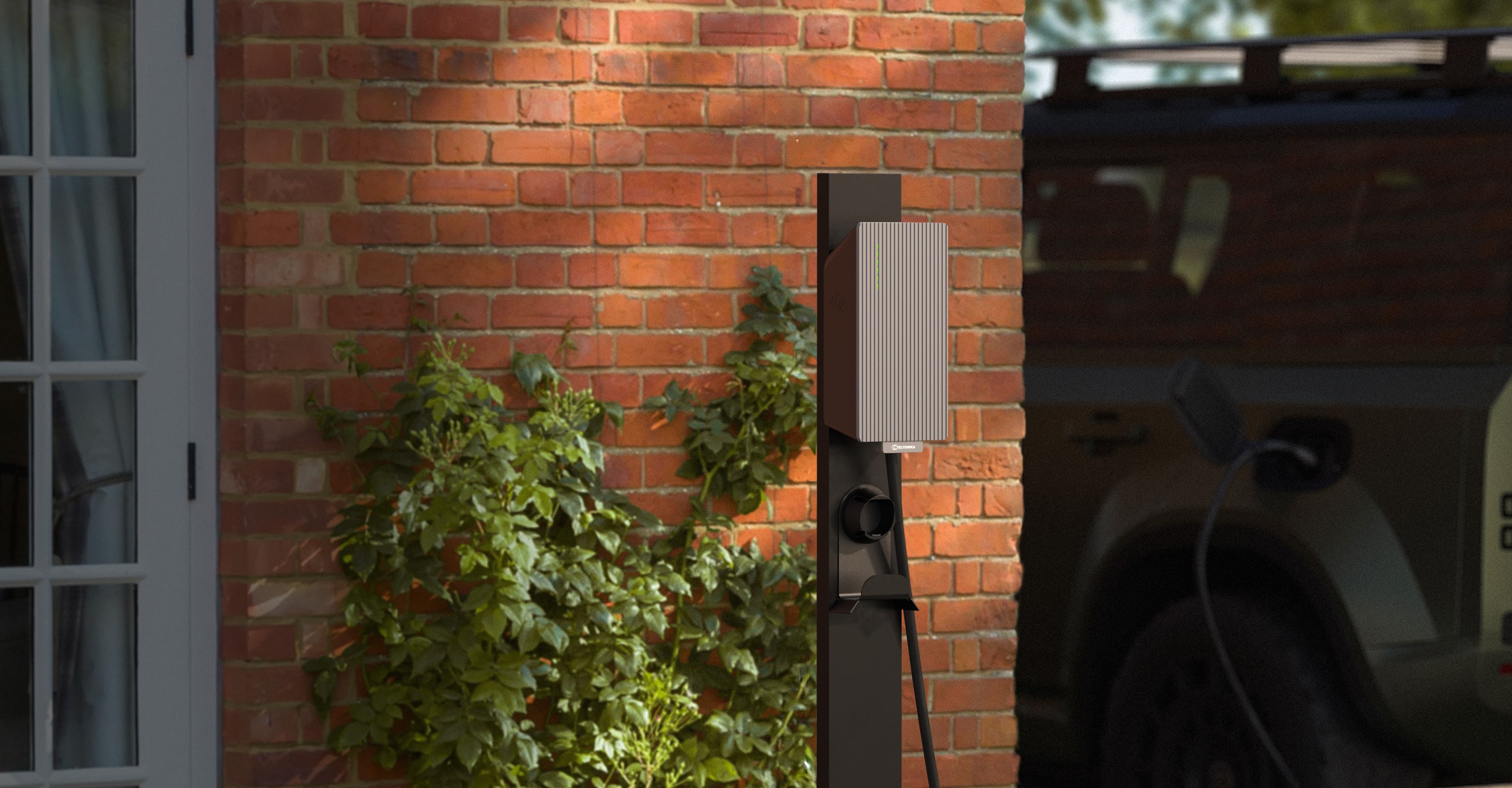 A Teltocharge AC EV charger mounted on a brick wall next to a parked car